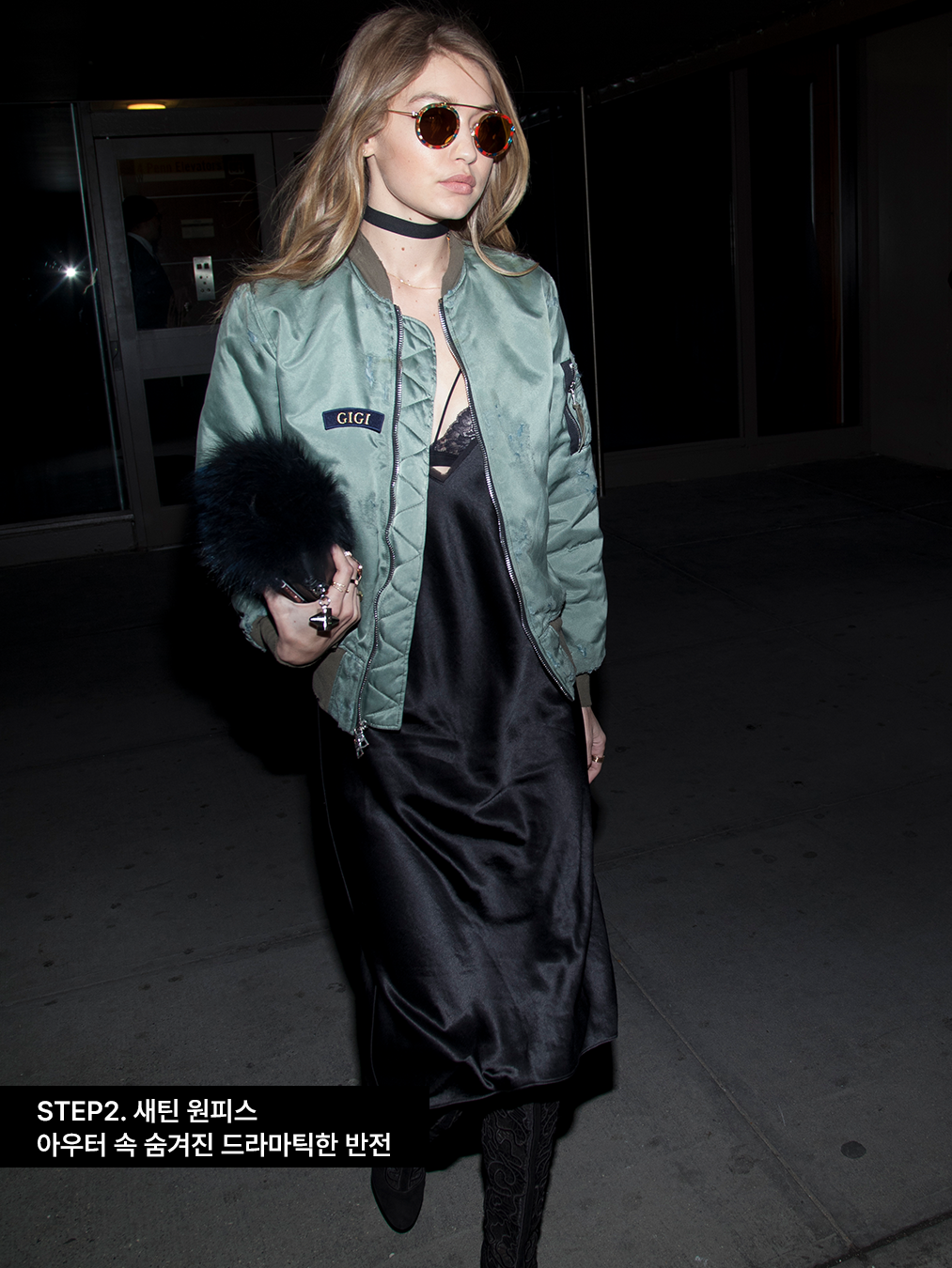 카키색 항공점퍼에 블랙 새틴 슬립 원피스를 입은 지지 하디드 gigi hadid