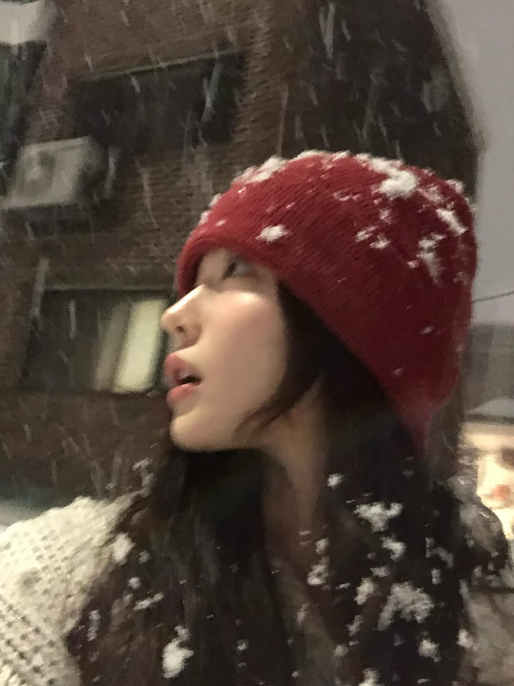 니트 아우터를 입고 빨간 니트를 쓴 채 눈을 맞는 배우 최윤지의 사진