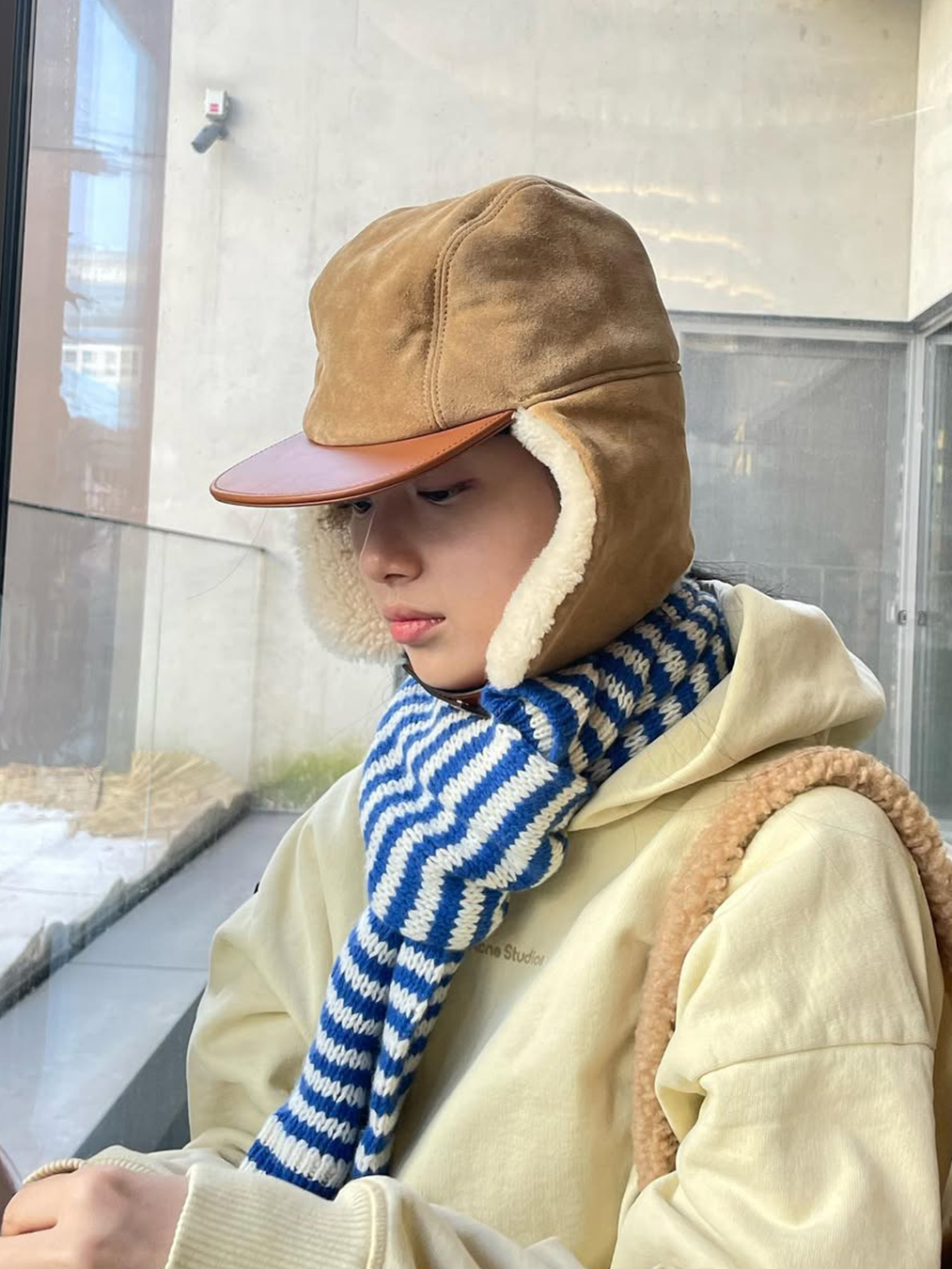 베이지색 무스탕 트루퍼햇을 쓰고 버터색 후드, 블루 스트라이프 머플러를 한 수지의 사진