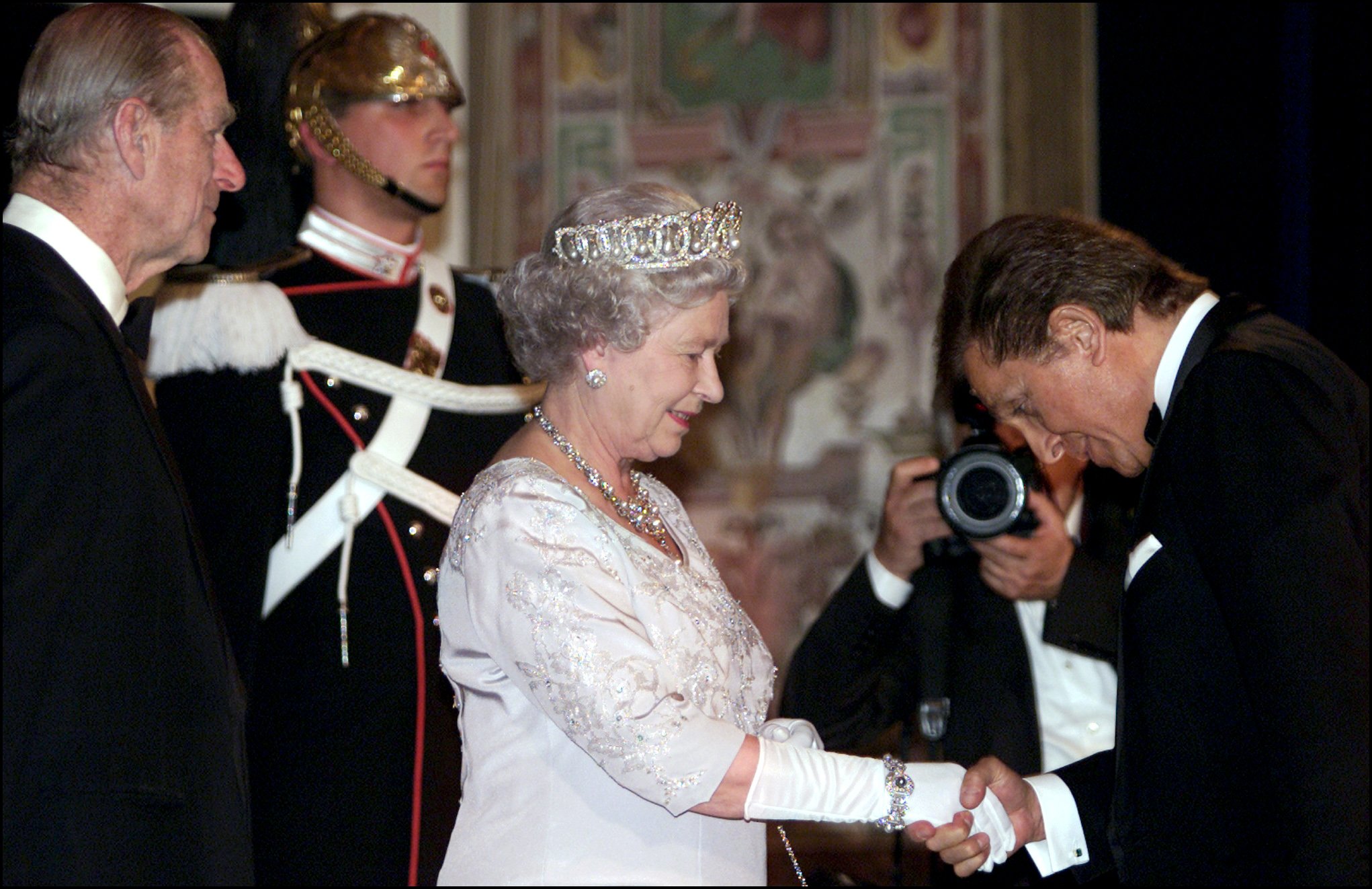 엘리자베스 여왕의 손을 잡고 있는 발렌티노 가라바니의 사진