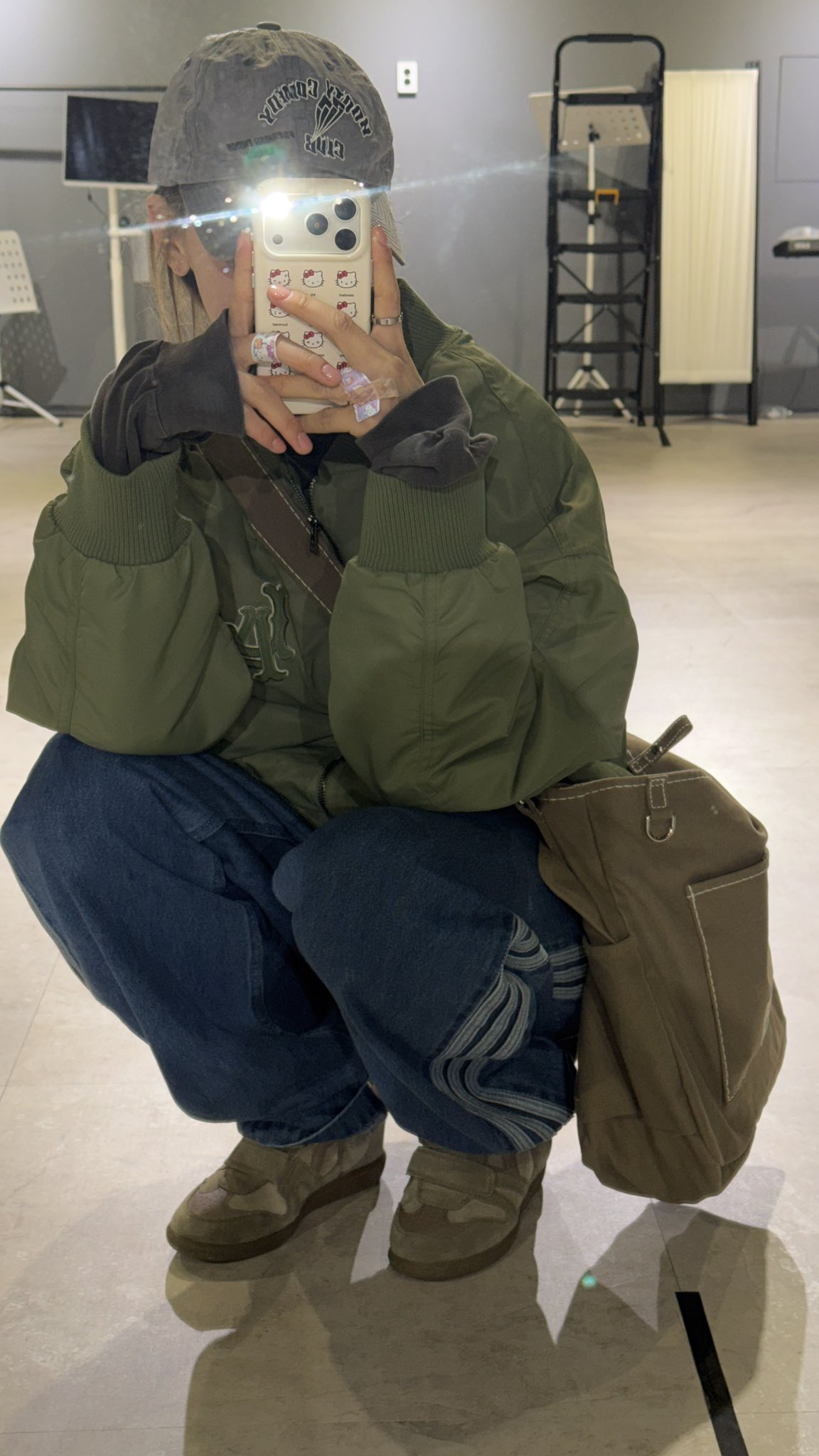 카키색 항공 점퍼와 브라운 톤 가방과 신발을 인디고 데님과 매치한 키스오브라이프 하늘