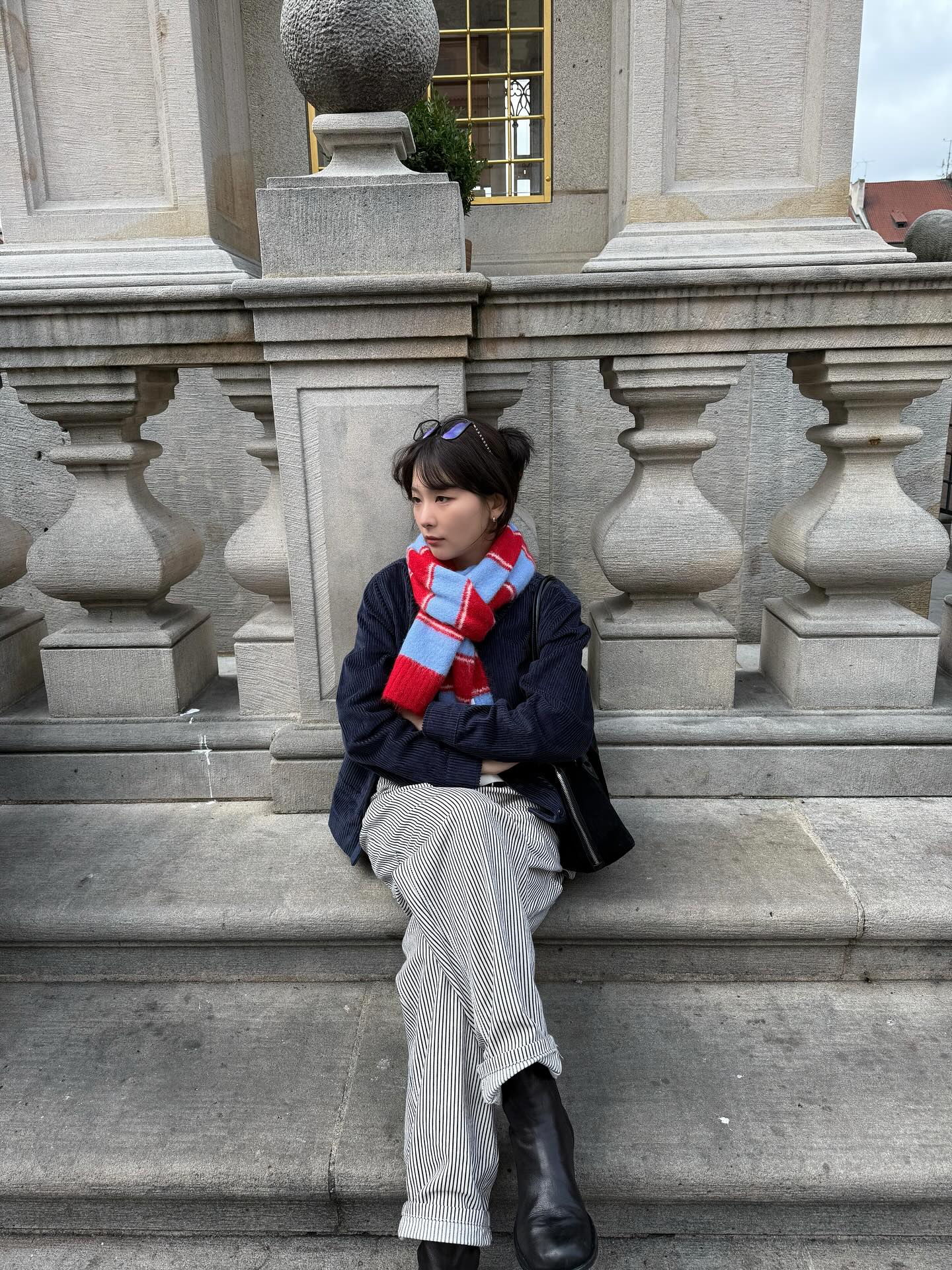 클래식한 네이비 재킷과 스트라이프 팬츠 위에 레드 체크의 따뜻함을 쿨 블루가 눌러주며, 전체 룩을 시원하게 정돈한 레드벨벳 슬기