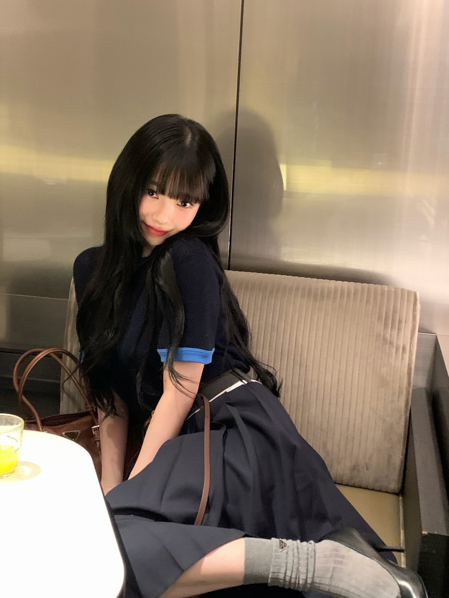 블루 트리밍이 들어간 네이비색 티셔츠, 그레이톤 플레어스커트와 니삭스를 신은 카리나