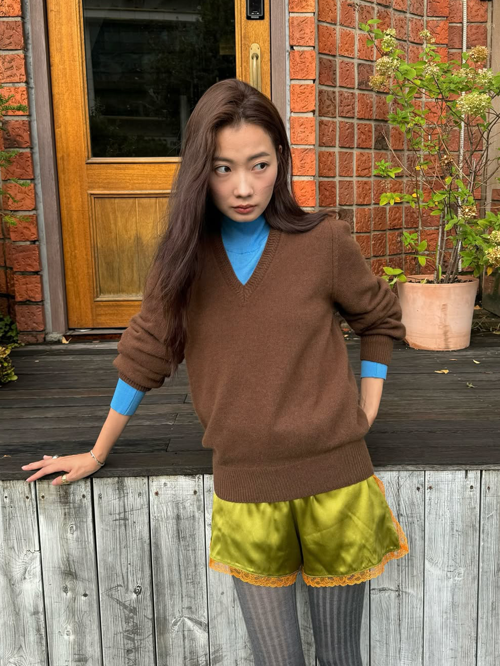 블루컬러의 터틀넥과 브라운 컬러의 브이넥 니트, 카키색 실크 소재 쇼츠와 그레이 컬러 스타킹을 매치한 인플루언서 박민주의 사진
