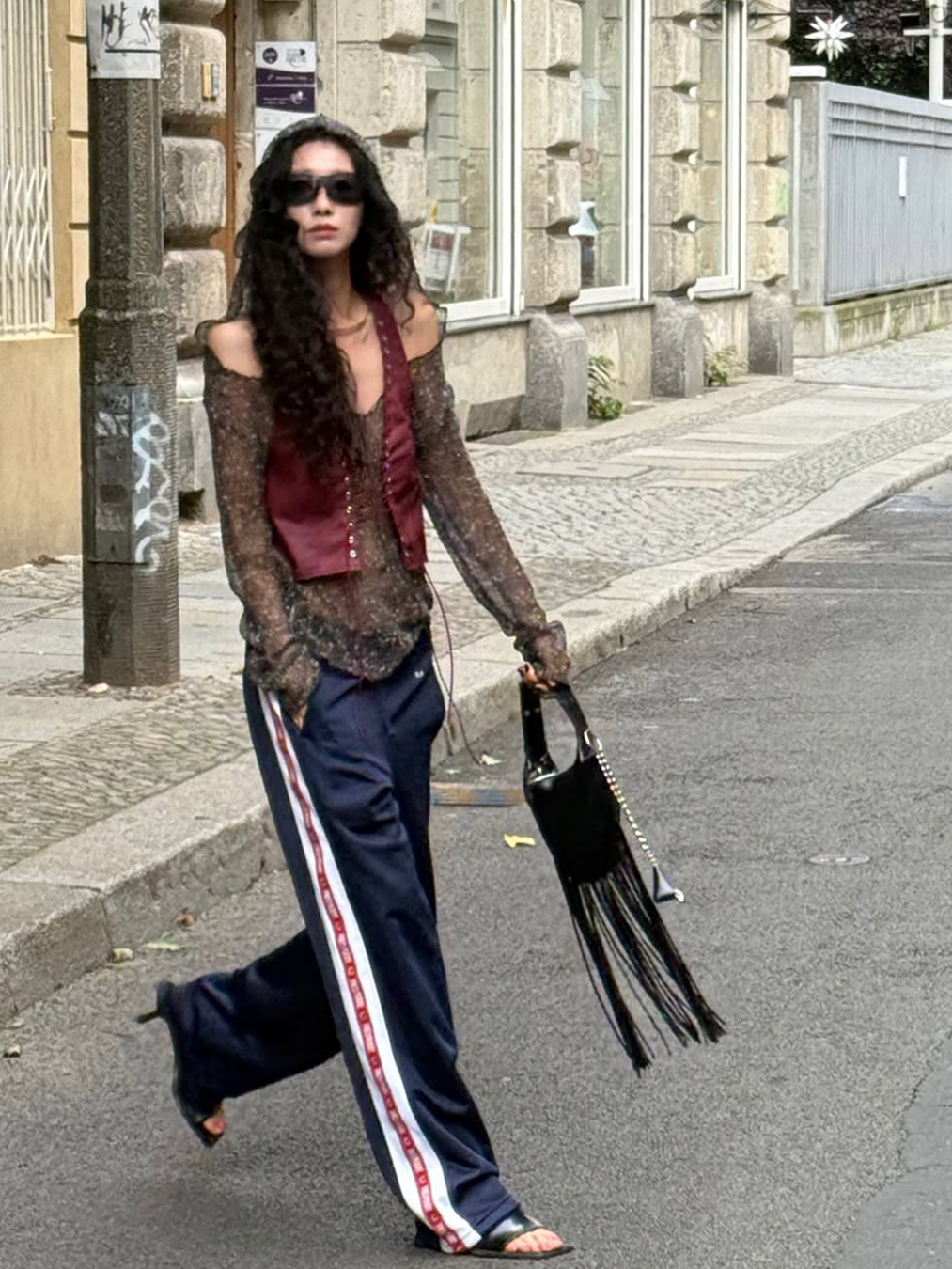 새틴 소재의 트레이닝 팬츠에 샌들 형태의 뮬 힐을 매치한 신지현의 사진 상의로는 브라운 컬러의 니트와 와인색 컬러 웨스턴 베스트를 매치했다