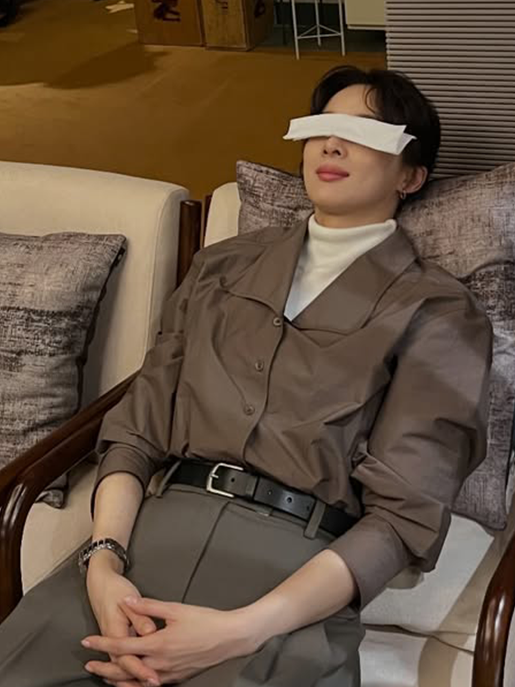 브라운 체크 셔츠와 애쉬빛이 도는 브라운 슬랙스를 입고 눈을 가린 채 휴식 중인 이청아의 사진