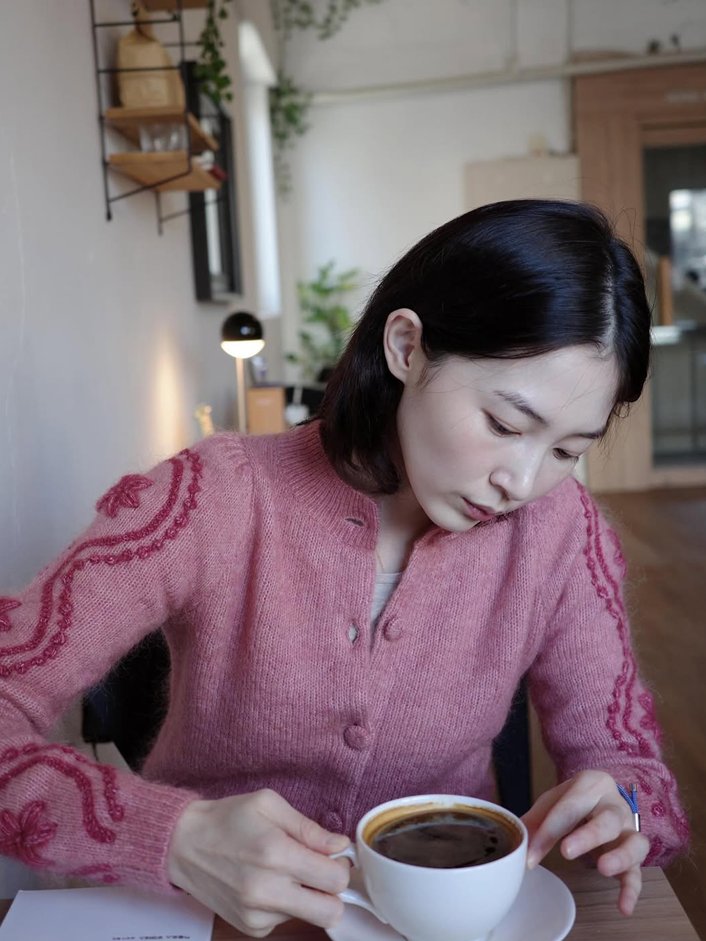 장미빛 니트 카디건을 입은 채 커피를 마시고 있는 배우 박유림의 사진