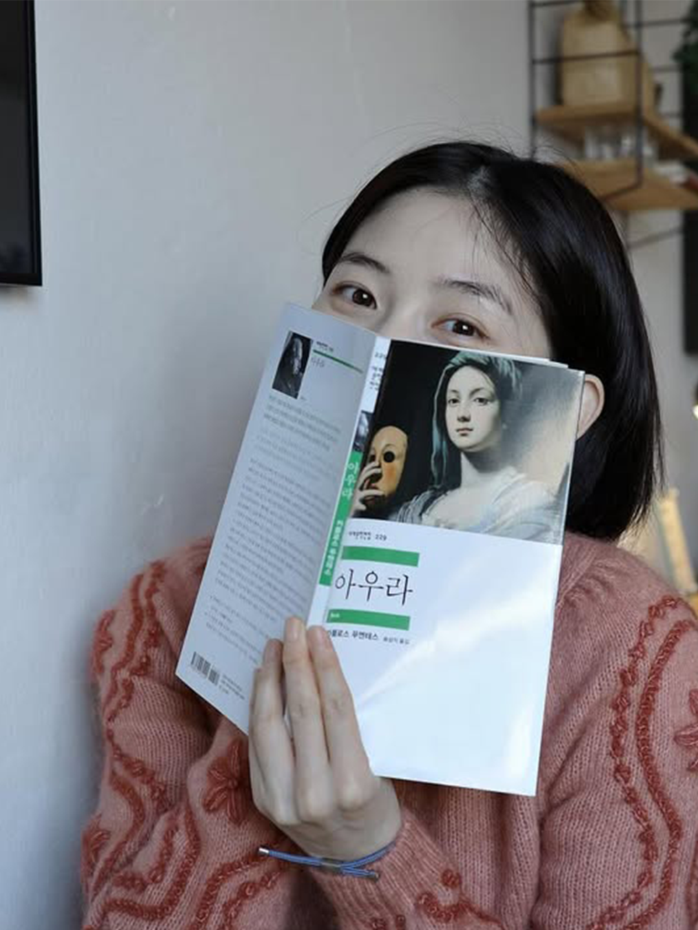 <아우라>라는 고전 소설책으로 얼굴을 반쯤 가린 배우 박유림의 사진