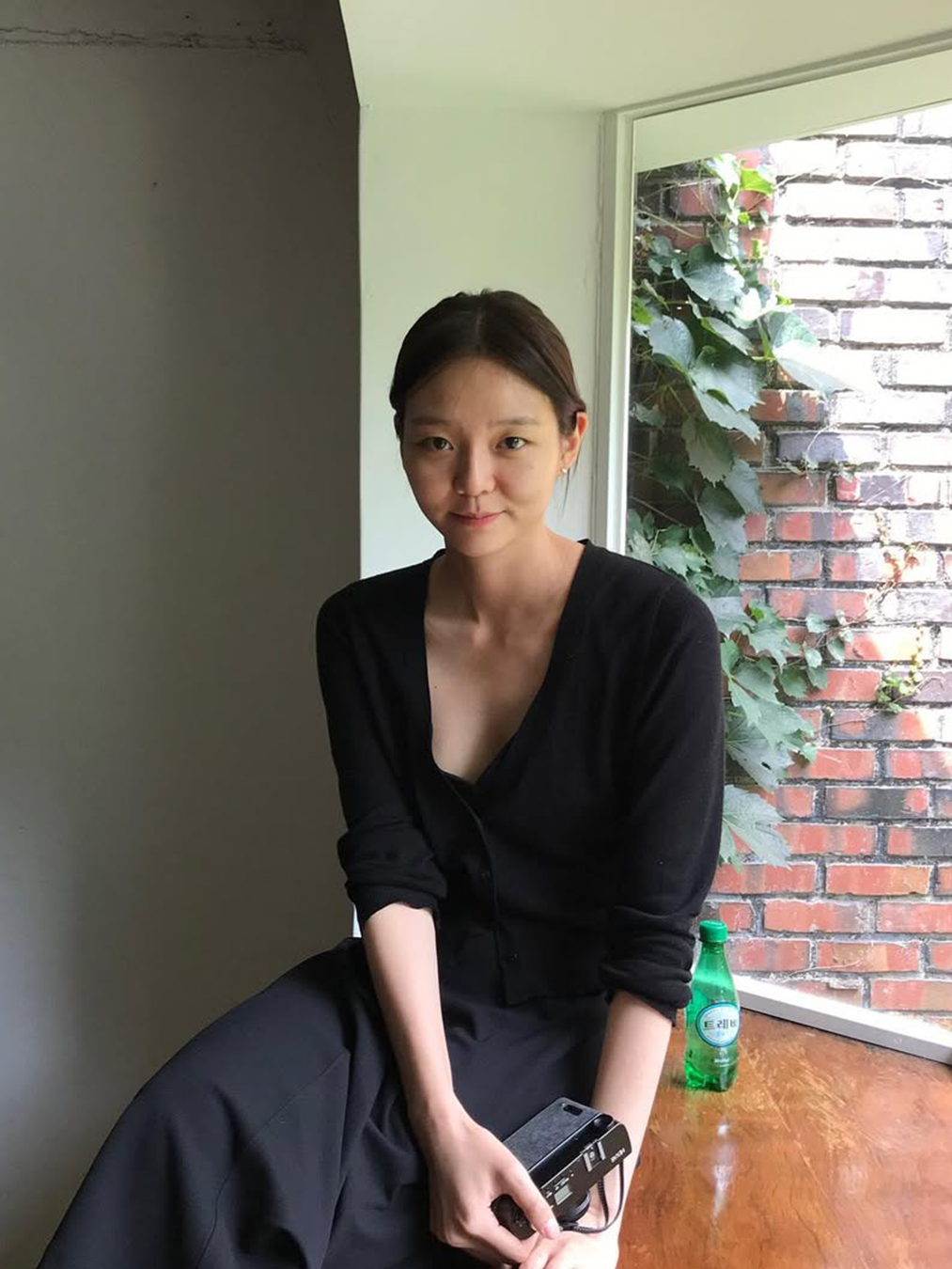 블랙 카디건, 블랙 와이드 팬츠를 입은 채 필름 카메라를 들고 있는 이솜의 사진